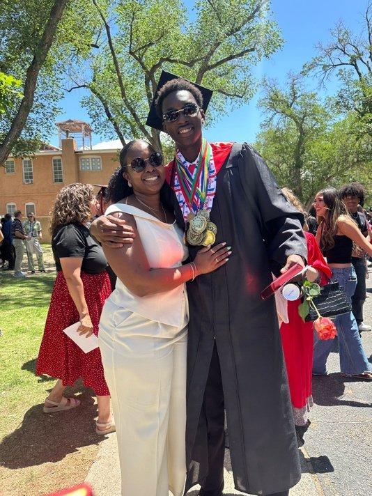 An Anguillian graduate celebrates with family after the Menaul High School ceremony